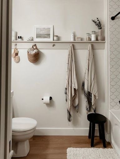 Moderne houten handdoekhouder met haken in een compacte badkamer.