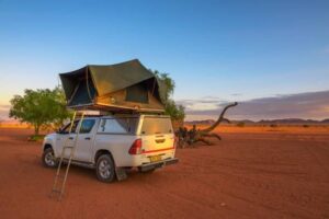 4x4 met daktent geparkeerd op rood zand in Namibië
