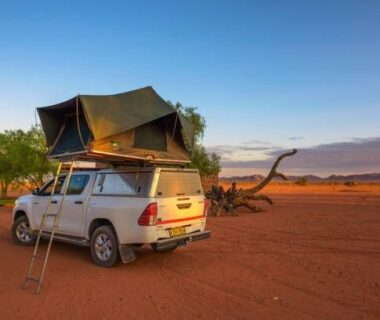 4x4 met daktent geparkeerd op rood zand in Namibië