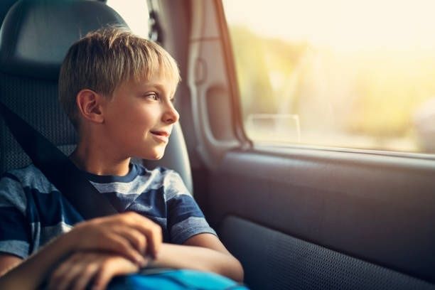 Jongen kijkt tijdens een lange autorit door het zijraam naar buiten